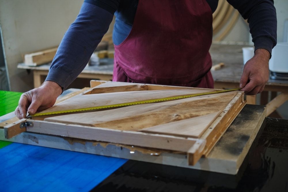 ASM craftsperson measuring timber in the workshop