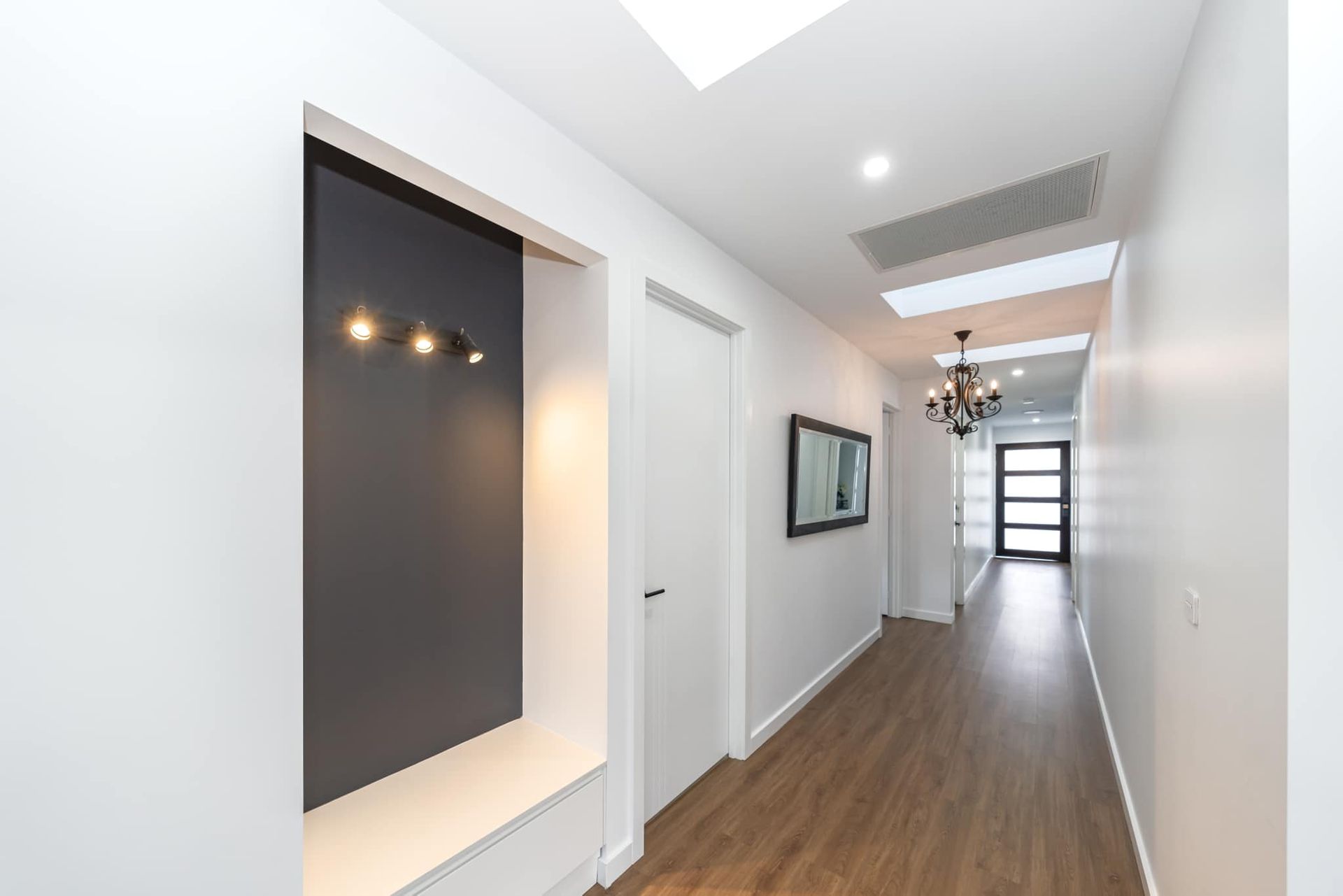 Long hallway with integrated white joinery and timber flooring